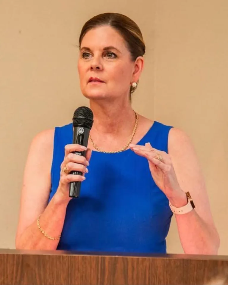 Carole Mendoza speaking at a podium in Savannah, Georgia